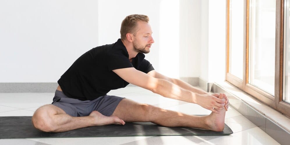 Man performing a hamstring stretch, highlighting the importance of recovery in workout routines for men.